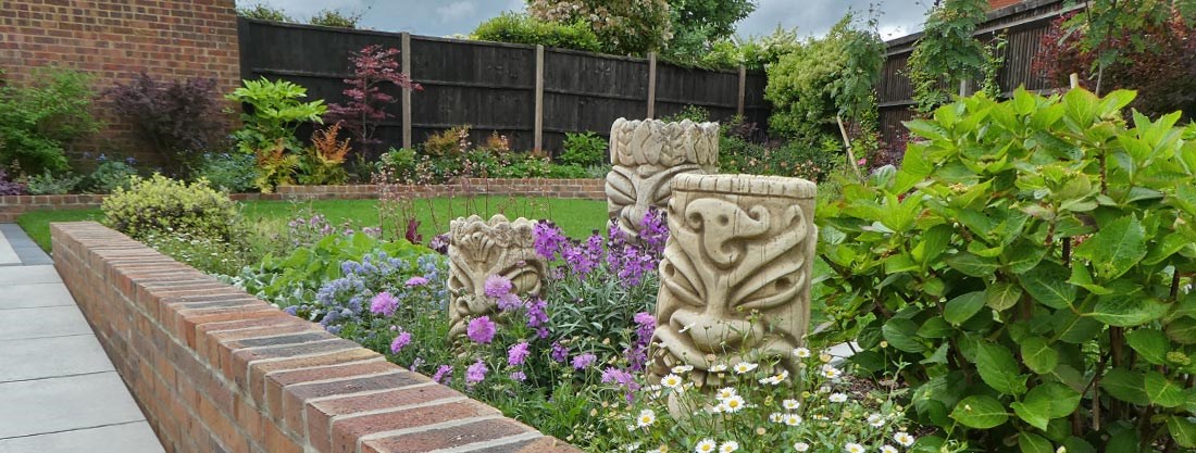 Accessible garden with a porcelain paved ramp, Māori inspired decorative heads and colourful planting
