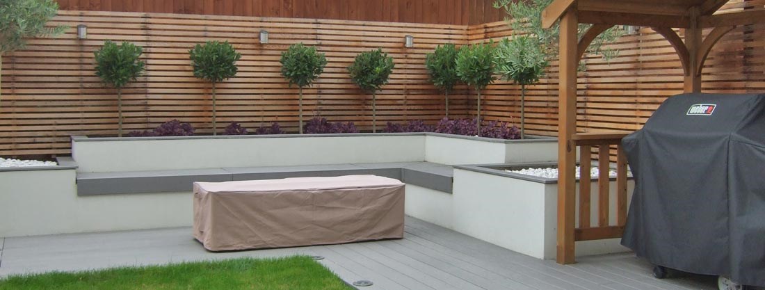 Contemporary BBQ area with composite decking and rendered planters with integrated bench seating