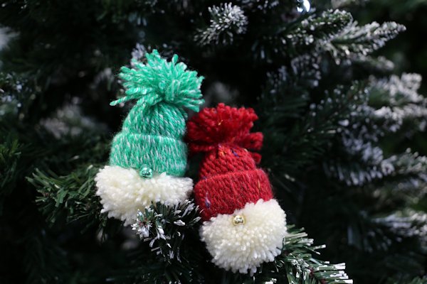 two pom-pom wool gonks sat upon an artificial christmas tree