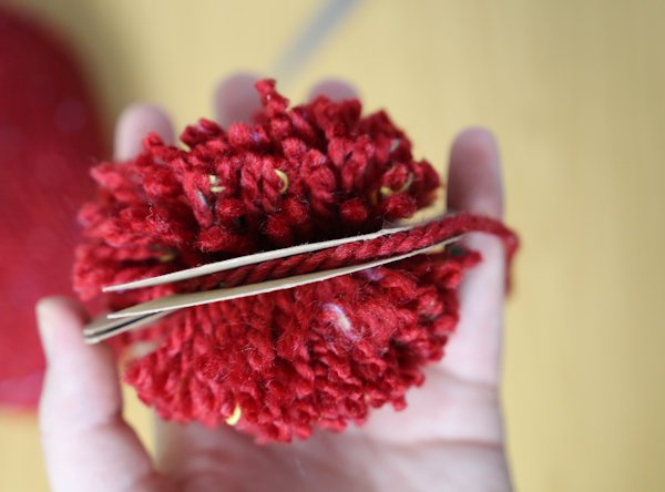 pom-pom being secured with string to hold it all in place