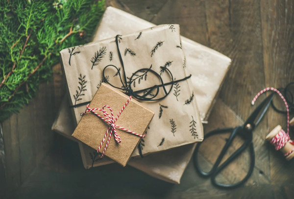 A stack of presents wrapped in brown Christmas wrapping paper and red twine